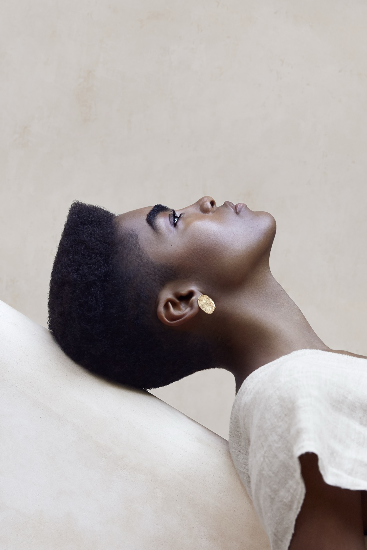 Beauty portret in profiel, crèmetinten en gouden oorsieraad