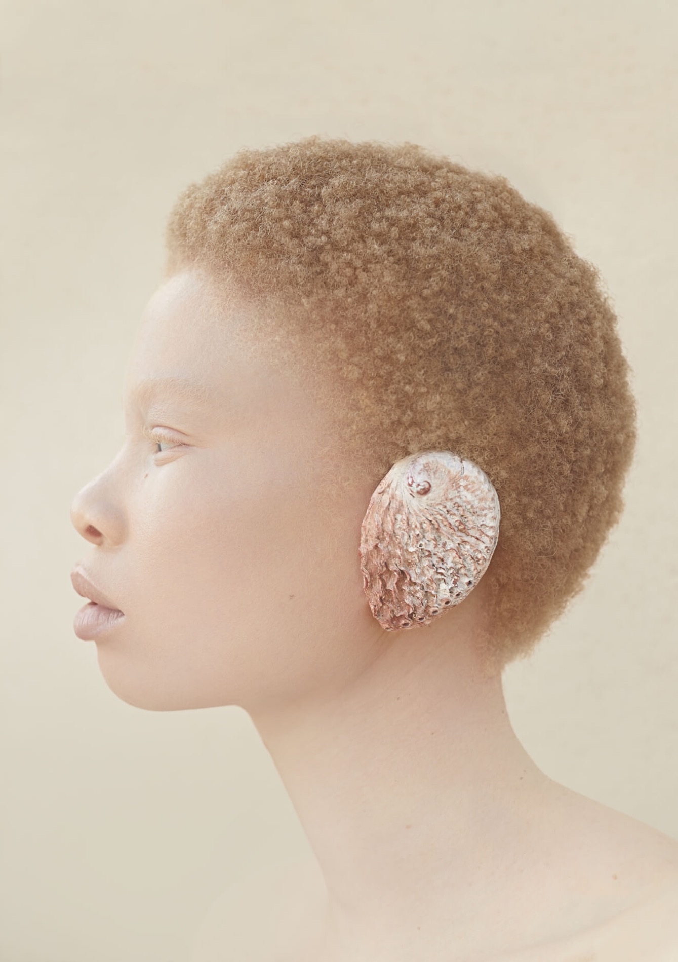 Hair editorial, abrikooskleurige afro in profiel met schelp-oorsieraad
